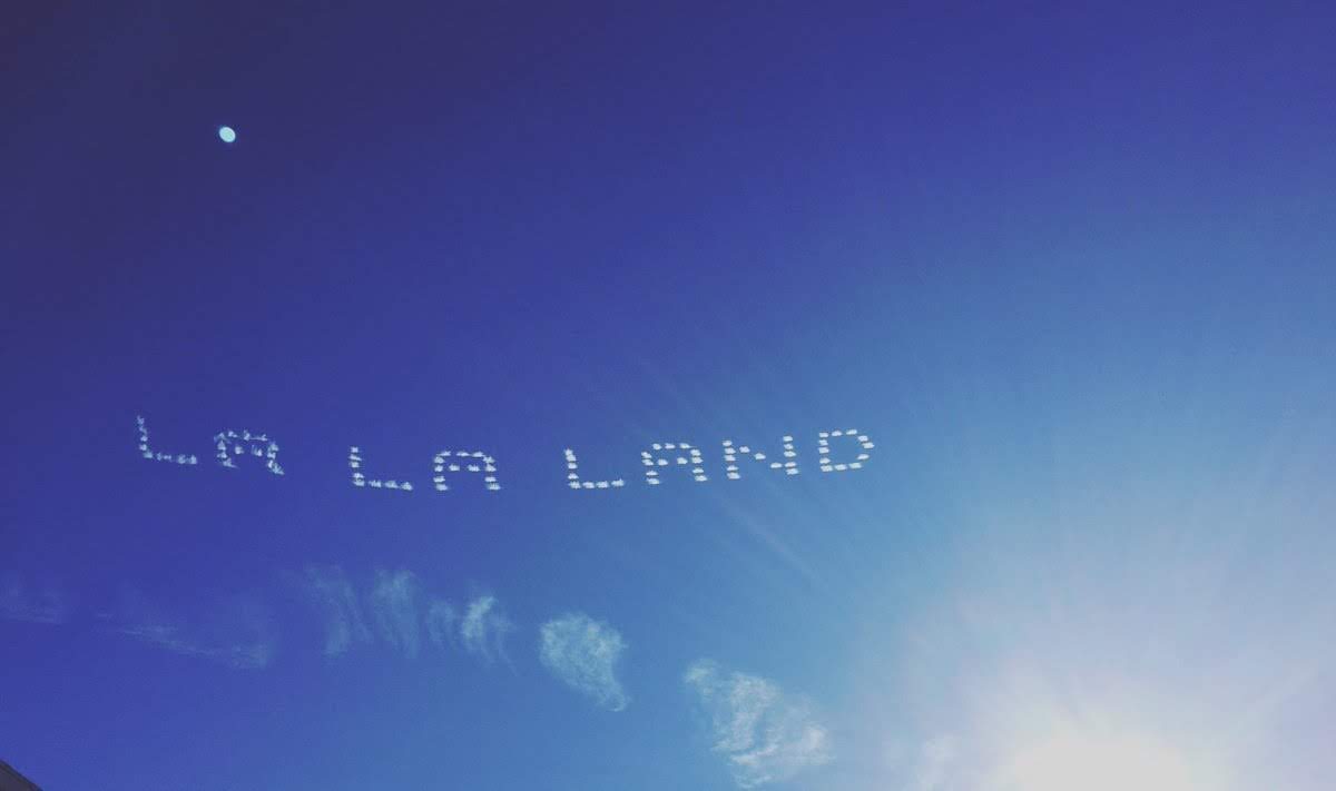 A plane flying in the sky with " la land " written on it.